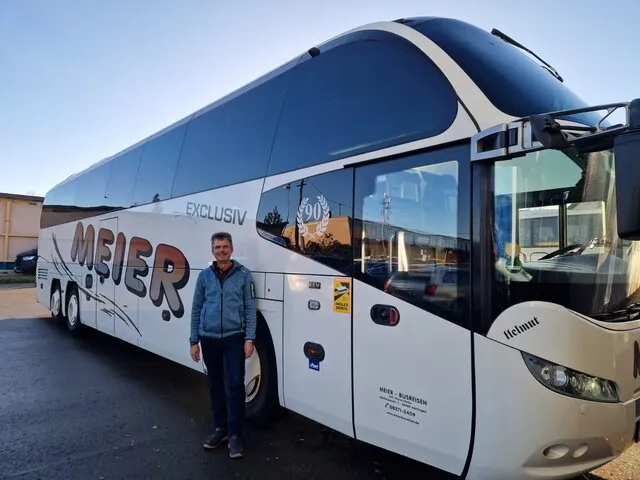 Helmut Haas steht neben einem weißen Reisebus von Busreisen Meier.